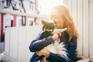 woman holding small dog outside