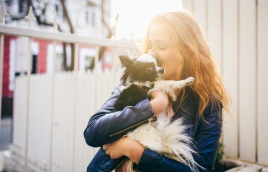 woman holding small dog outside