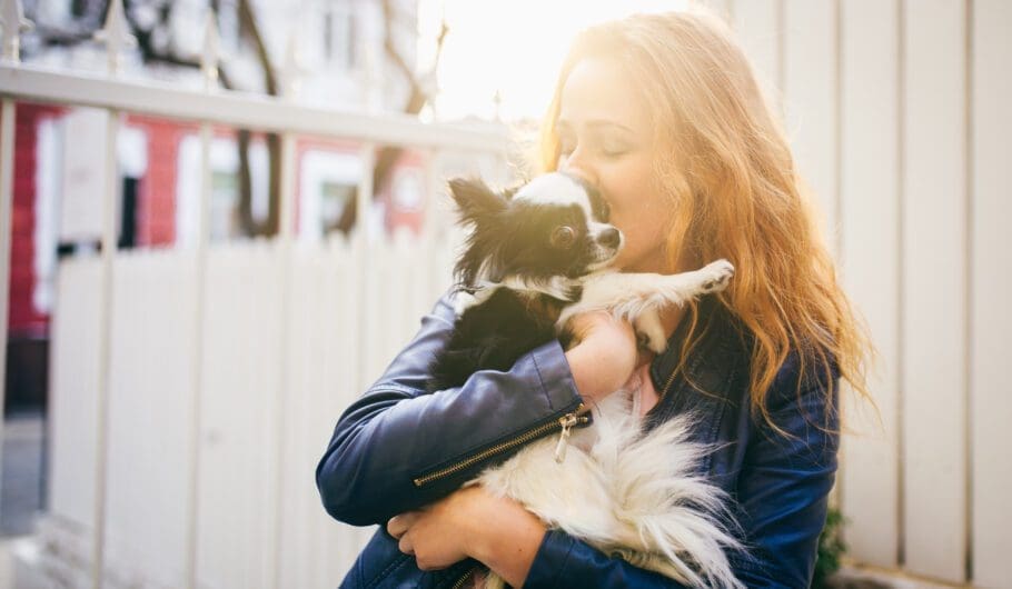 woman holding small dog outside