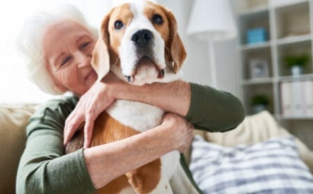 senior woman hugging emotional support dog on a couch