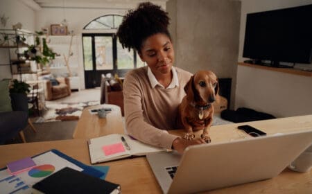 A young woman with a dog researching how to get an ESA letter on her laptop.
