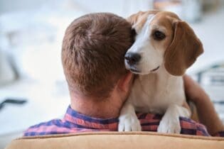 blond man hugging beagle