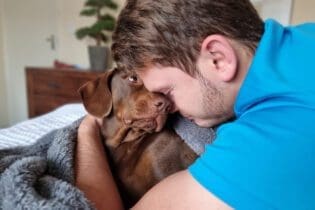 man hugging brown labrador