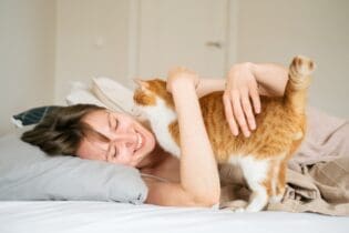 woman smiling cuddling cat