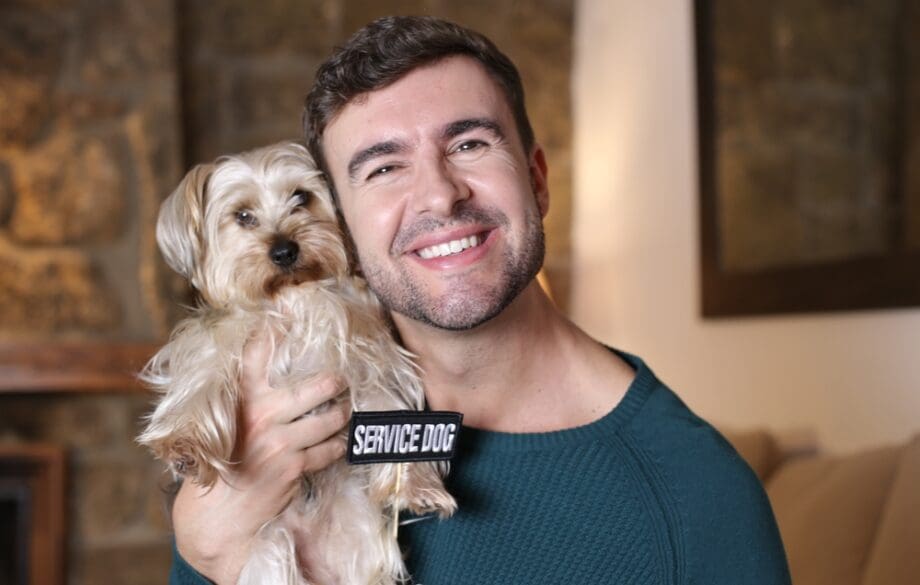 smiling man holding small service dog