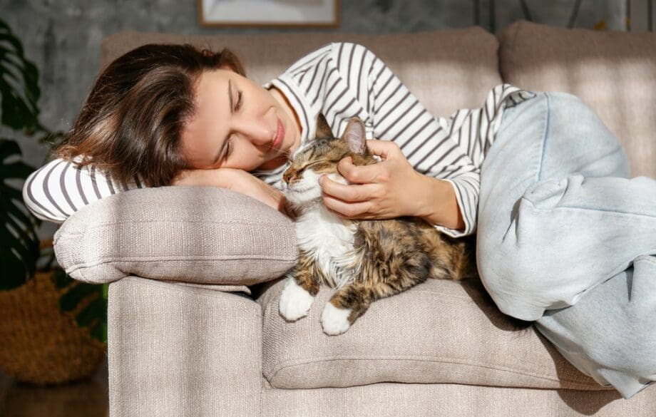 woman cuddling with cat on couch