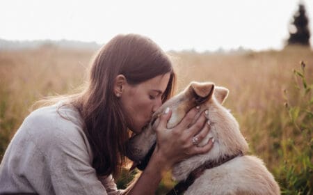 woman kissing dog in the field