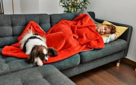 woman and dog laying on couch