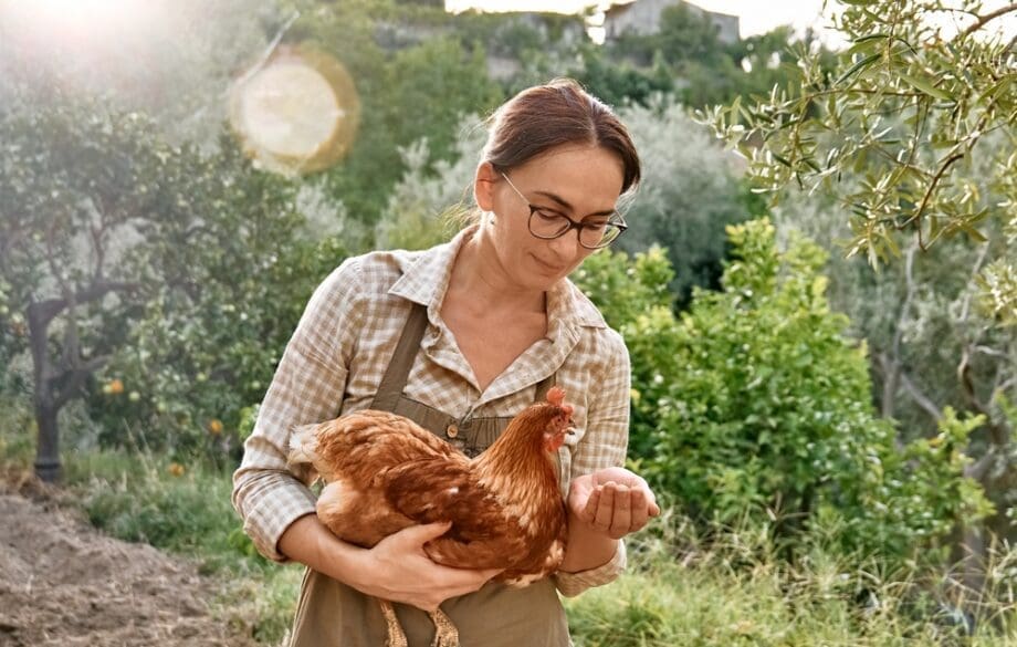 A woman holding emotional support chicken on farm