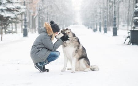 A woman cradles her husky service dog’s face while on a walk.
