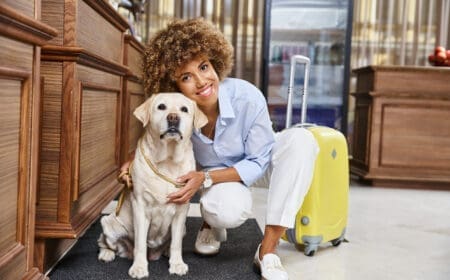 A woman sitting beside her Labrador retriever inside a Motel 6 lobby, while wondering, is Motel 6 pet friendly?